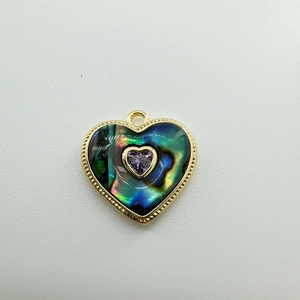 Macro detail of a 18K gold-plated heart pendant with abalone shell and purple gem