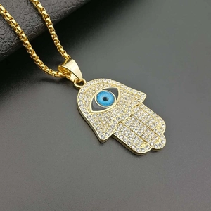 Gold Hamsa hand pendant necklace with blue eye and crystals on a polished link chain
