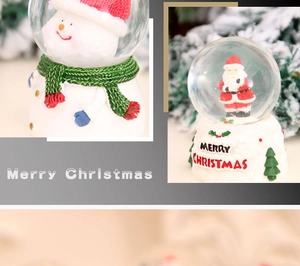 Close-up of Christmas crystal balls featuring snowman and Santa with pine branch decor