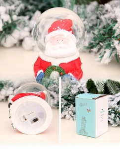Detail showing Christmas Santa snow globe with base power switch and gift box packaging