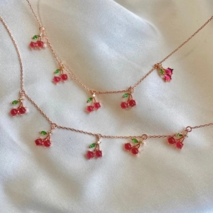 Rose gold cherry pendant necklace with red and pink zircon crystals on white silk