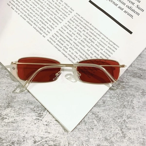 Detail of vintage rectangular sunglasses with red lenses and slim gold metal temples
