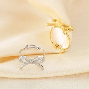 Detail of gold and silver bow rings on silk fabric showing the adjustable open band