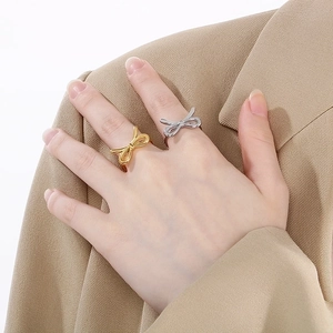 Close-up of minimalist gold and silver bow rings worn on fingers with a sleek metal finish