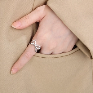 Minimalist silver bow-shaped stainless steel open ring worn on a hand over a suit pocket