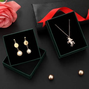 Detail of unicorn necklace and pearl coin earrings in a dark green velvet jewelry box