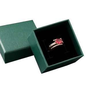 Golden ring with red ruby gemstone and side diamonds in a dark green jewelry gift box