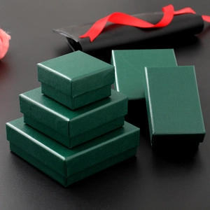 Dark green jewelry gift box set with elegant red ribbon on a professional black background