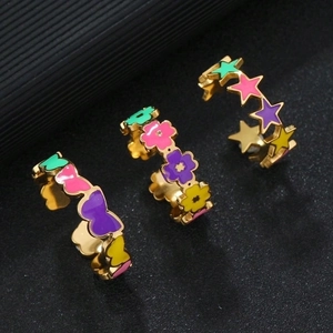Three colorful enamel stainless steel rings with heart flower and star shapes on black background