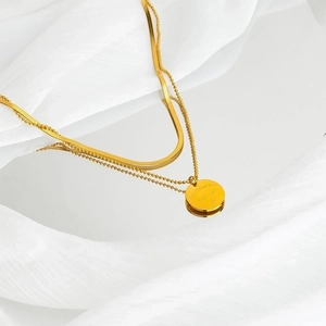 Detail of 18k gold plated double layered necklace with engraved round pendant and coin charm