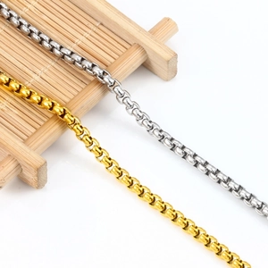 Polished gold and silver stainless steel box chain necklaces on a bamboo mat background