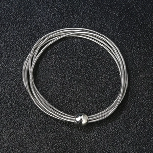 Unisex stainless steel spring bracelet with a polished silver ball charm on black background