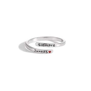 Macro shot of silver ring engraved with Siempre Juntas and a tiny red heart