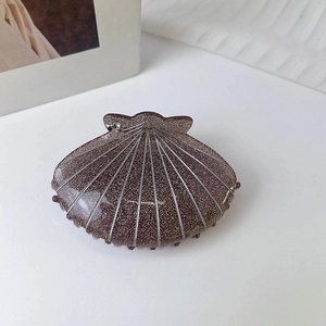Detail of shell-shaped hair claw clip in dark brown with silver glitter and rhinestone