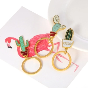 Macro view of three enamel cactus charms with gold metal rings on a floral display card