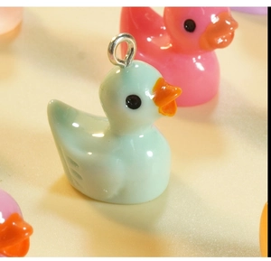 Macro shot of mint green and pink resin duck pendants with silver metal loops for DIY jewelry