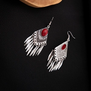 Macro detail of Bohemian silver earrings with red stone and hanging metal tassels