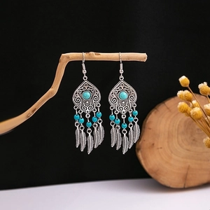 Macro shot of silver boho earrings with blue turquoise beads and hollow floral carvings