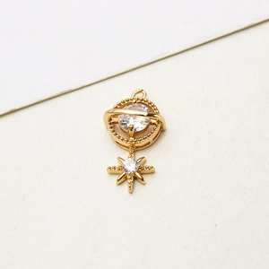 Detailed close-up of a gold Saturn-shaped pendant featuring sparkling clear zircon stones