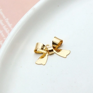 Macro shot of a golden bow-knot jewelry pendant on a white ceramic plate