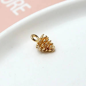 Detailed macro view of a gold pine cone pendant with scales for DIY jewelry making