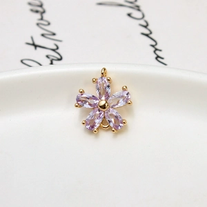 Macro view of purple zircon flower pendant with gold plating on white ceramic