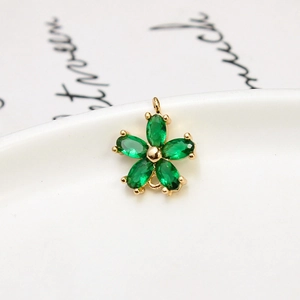 Macro shot of a gold flower pendant with five marquise-cut green zircon petals on ceramic