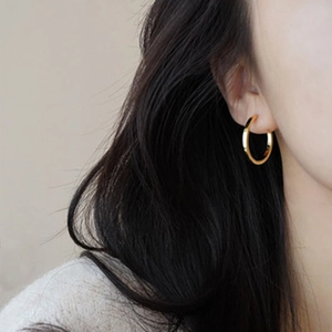Close-up of minimalist golden hoop earrings worn by a model for a stylish look