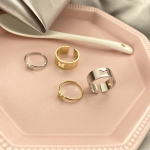 Detail view of gold and silver butterfly ring set on a pink ceramic jewelry tray
