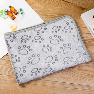Detailed view of gray pet blanket with dark paw prints on a wooden surface