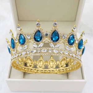 Detailed view of a golden crown with blue teardrop stones in a white gift box