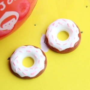 Macro shot of realistic chocolate donut resin accessories with white frosting and pink sprinkles