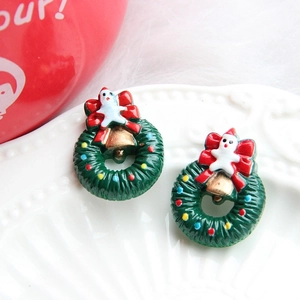 Close-up of festive Christmas wreath earrings with red bows and colorful resin ornaments