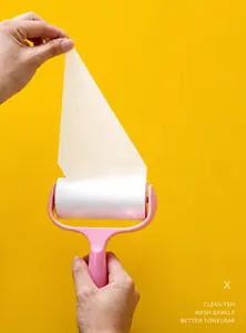 Detail showing the easy-tear diagonal pink handle lint roller for home clothing cleaning