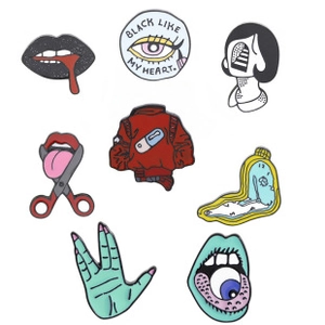 Detail of surreal enamel pins including melting clock and black heart eye designs