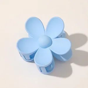 Macro view of matte light blue flower hair claw clip with smooth five-petal design