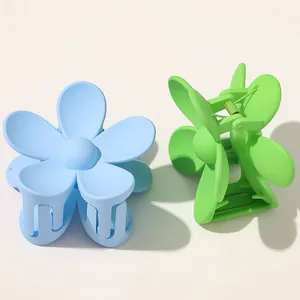 Detail view of sky blue and lime green matte flower hair claws with a textured finish