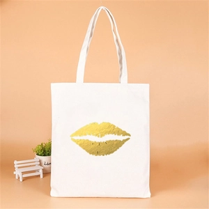 Close-up of white canvas tote bag featuring a gold foil lip print for bridal parties