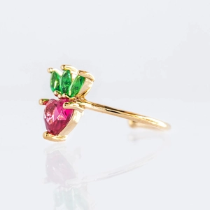 Detailed side view of a gold strawberry jewelry piece with red heart-shaped zircons