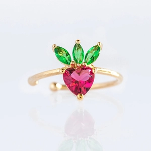 Macro shot of gold strawberry ring with red heart zircon and green gemstone leaves
