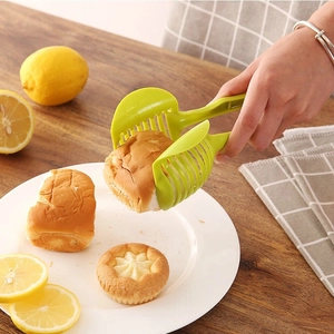 Green plastic lemon and bread slicer tool on a wooden table for precise slicing