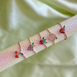Colorful fruit-themed gold rings featuring strawberry peach and grape crystal designs