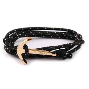 Detail of black nylon rope bracelet with white dots and gold Viking anchor clasp