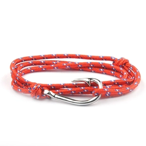 Red braided nautical bracelet with a metallic fish hook anchor clasp on white background