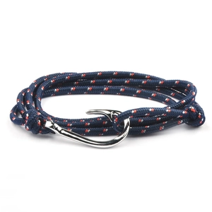 Detail view of navy blue woven nautical bracelet with silver fish hook clasp and red accents