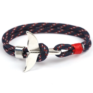 Close-up of nautical woven rope bracelet featuring a polished silver whale tail charm