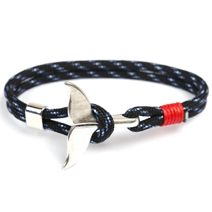 Macro detail of hand-woven black and blue paracord bracelet with silver whale tail clasp