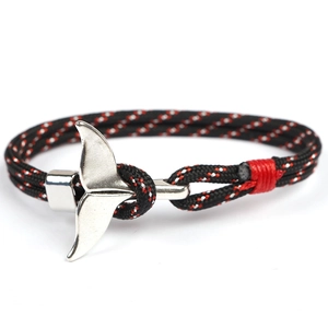 Detail of red and black paracord bracelet with a silver whale tail anchor clasp on white background