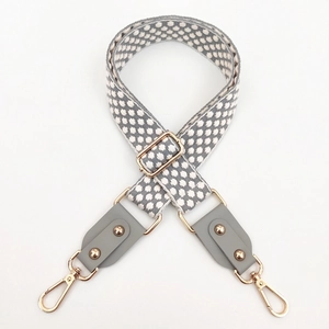 Macro detail of adjustable woven checkered bag strap with grey leather and gold hooks