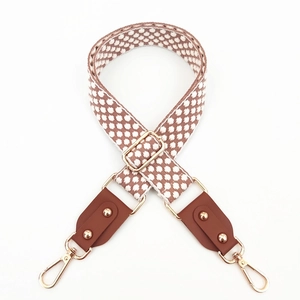 Detail of adjustable embroidered bag strap with polka dots, leather ends and gold buckles